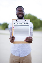 man holding a volunteer signup sheet on a clipboard 