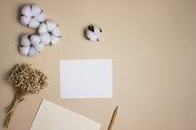 Blank note on tan background with cotton and dried flowers