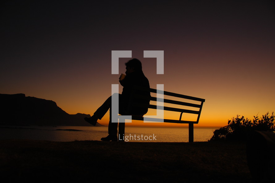 silhouette sitting on a bench at sunset 