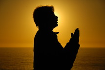 silhouette of a man with praying hands 