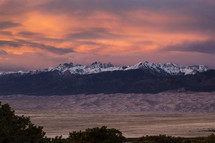 Sunset behind a snow covered mountain range.
