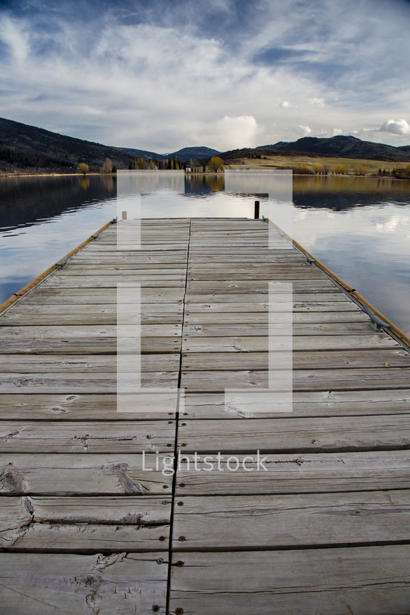 A wooden pier reaching into a placid lake.