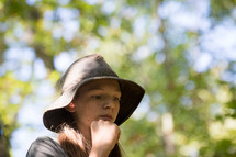 teen girl in a hat standing in a forest 