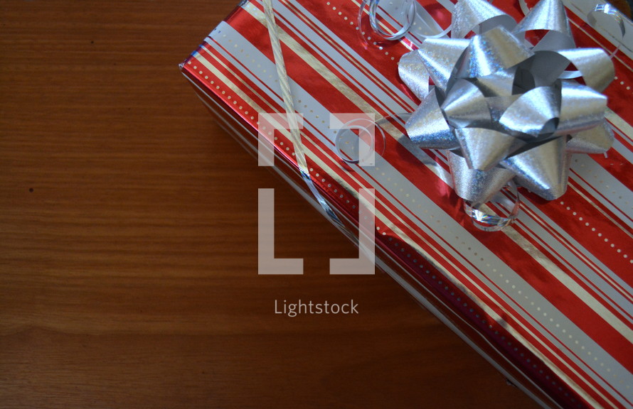 A gift wrapped in red striped paper with a silver bow.