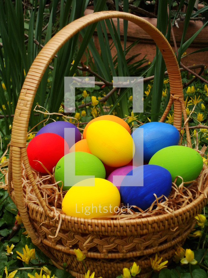 brightly colored Easter eggs in a basket outdoors 