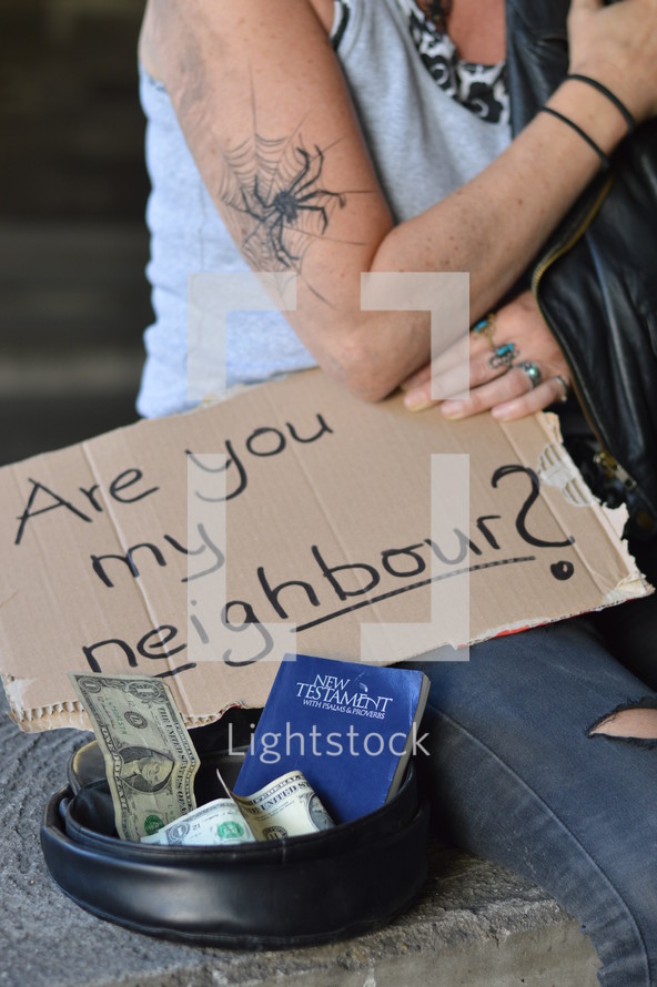 homeless woman begging for money holding a sign - are you my neighbor? 