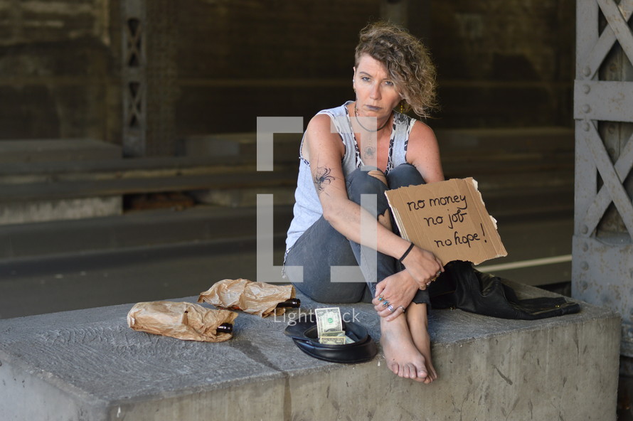 a homeless woman holding a sign and begging for money