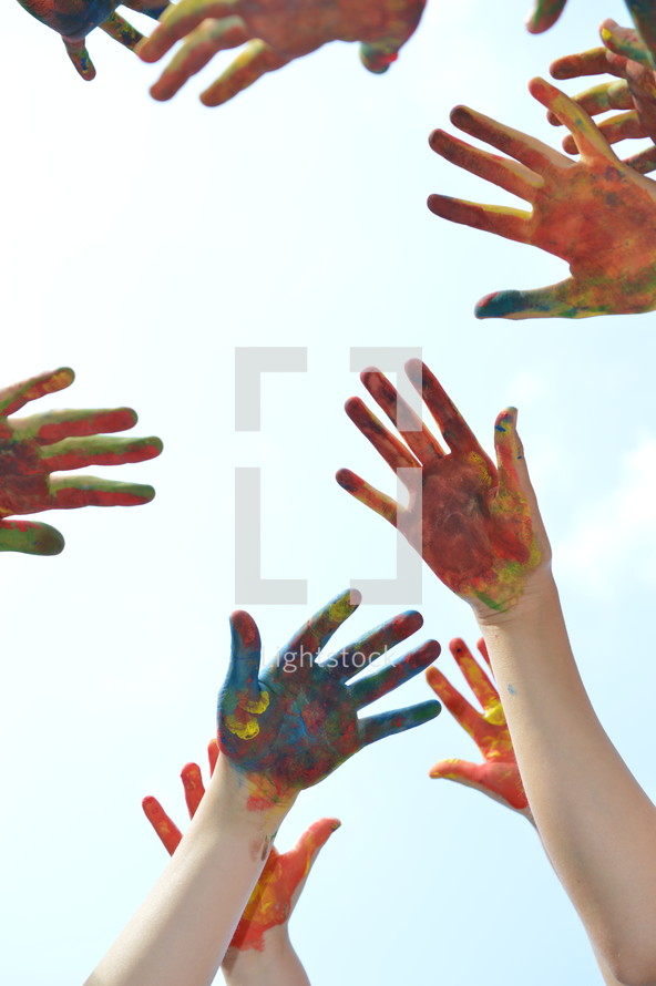 finger paint on the hands of kids with raised hands 