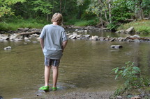 boy standing in shallow water 