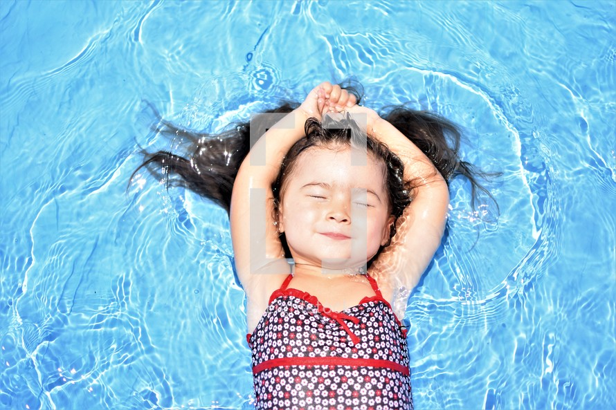 a toddler girl floating in a pool 