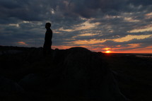 silhouette of a man standing outdoors at sunset 