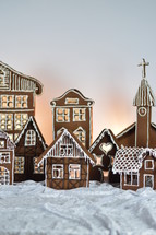 home made gingerbread village with church in front of white background on white snowlike velvet as advent decoration
