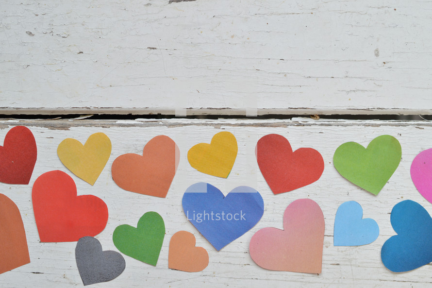 colorful paper hearts on a white wood background 