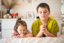 children praying at a bedside 