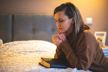 a woman praying bedside 