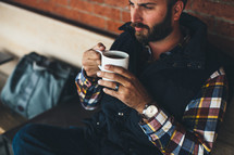 man sitting holding a cup of coffee 
