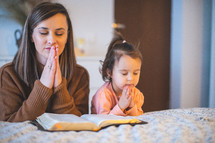 a mother reading the Bible to her toddler daughter 
