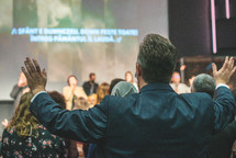 parishioners with raised hands during a worship service 
