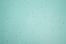 Turquoise background with blue and white snowflake confetti