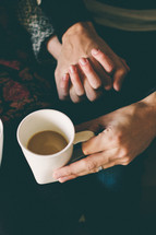 couple holding hands and coffee mug