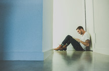A man sitting in a hallway reading a Bible 