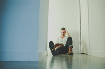 A man sitting in a hallway reading a Bible 