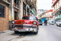 Side street in Downtown Havana, Cuba, an antique car sits on the side of the road as a horse and buggy prepare to pass