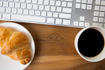 croissant, coffee cup, and computer keyboard 