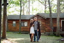 a couple wrapped in blankets in front of a log cabin