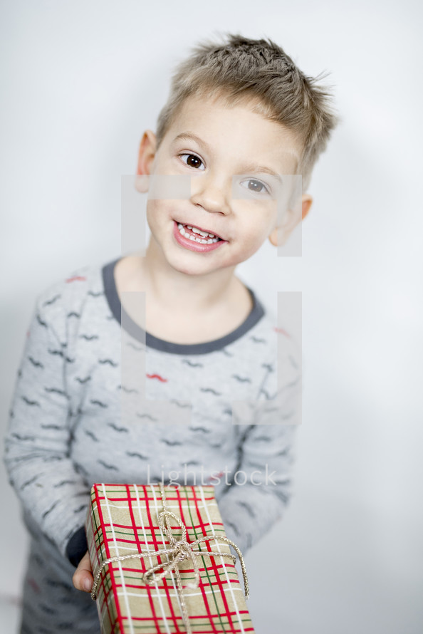 little boy in pajamas holding a gift 