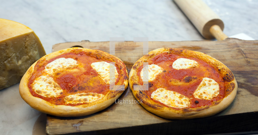 Two small pizza margherita on wood cutting board