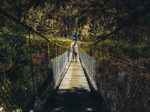 man walking across a swinging bridge 