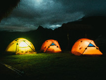 Tents glowing with light on a mountaintop.
