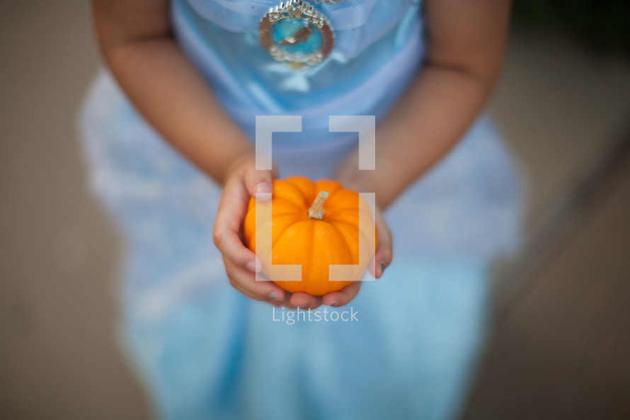 a child in a princess costume holding a pumpkin 