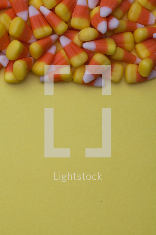 border of candy corn on a yellow background 