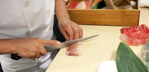 Hand was sliced fish to make sushi in chelsea market, New York.