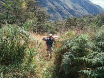 man hiking through dense vegetation 
