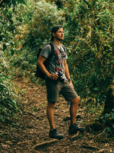 man with a camera standing in a jungle 