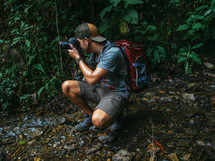 man taking a picture with a camera in a jungle 