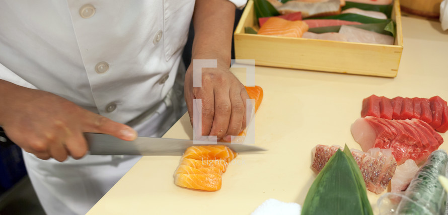 Hand was sliced fish to make sushi in chelsea market, New York.