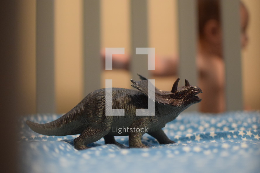 a dinosaur toy in a crib and infant 