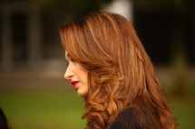 side profile of a woman with red hair and red lips 