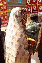 woman in a scarf holding flowers in India 
