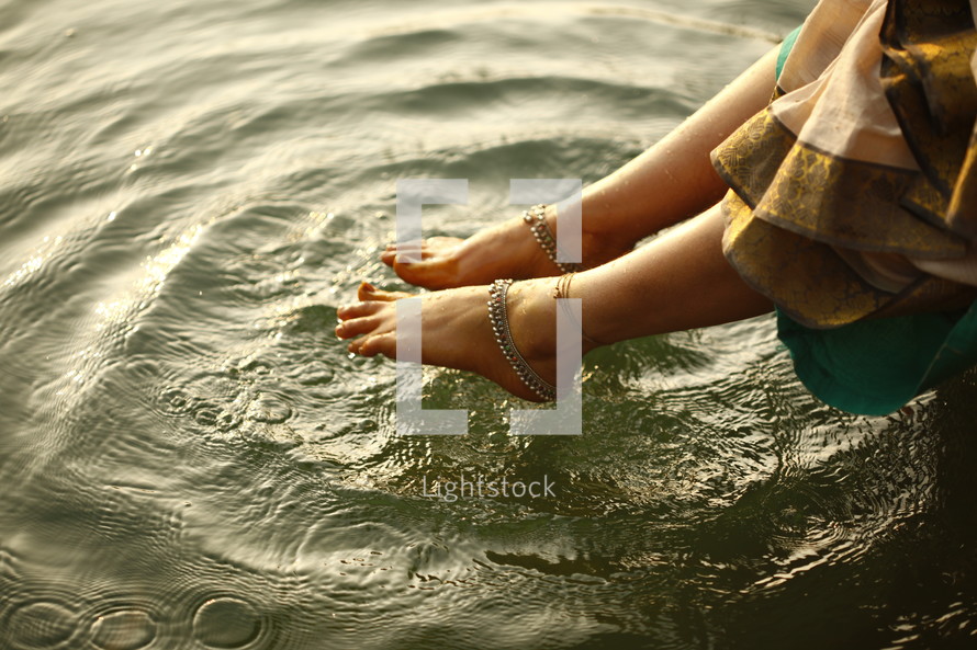 woman with her feet hanging over water 