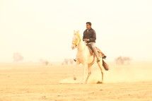 man riding a horse in the desert 