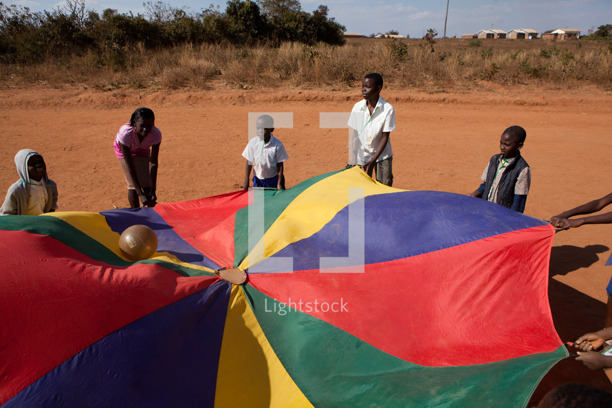 children playing with a ball and parachute in Malawi, Africa. 