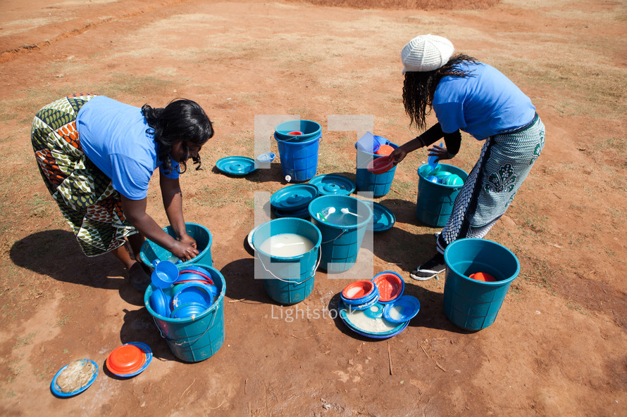 Woman washing dishes in buckets in Malawi, Africa. 