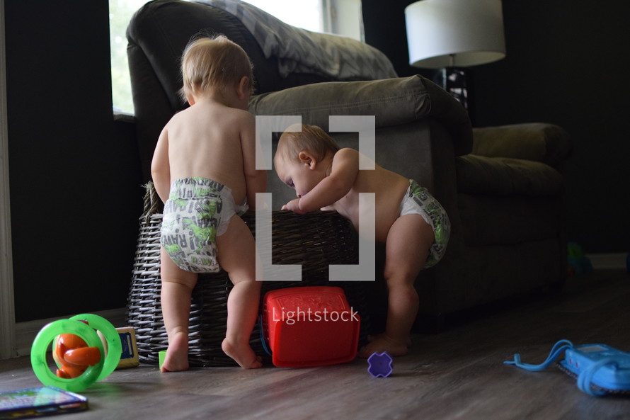 infants in diapers playing in a toy basket 