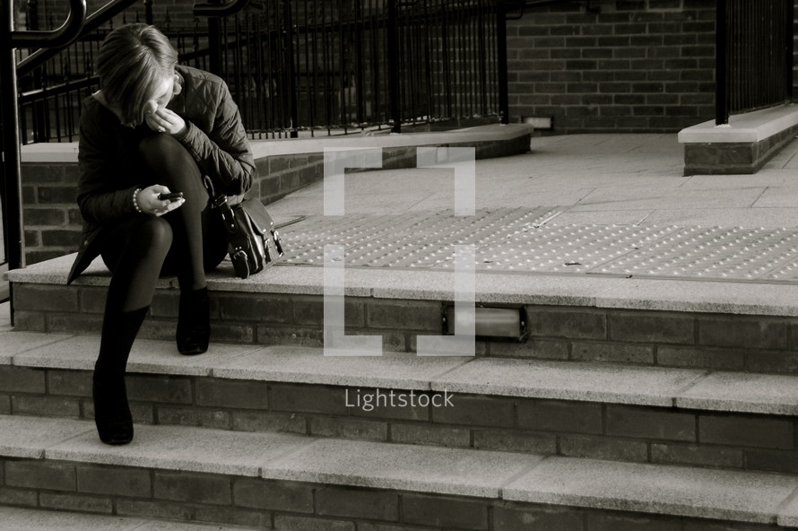woman on steps looking at her cell phone