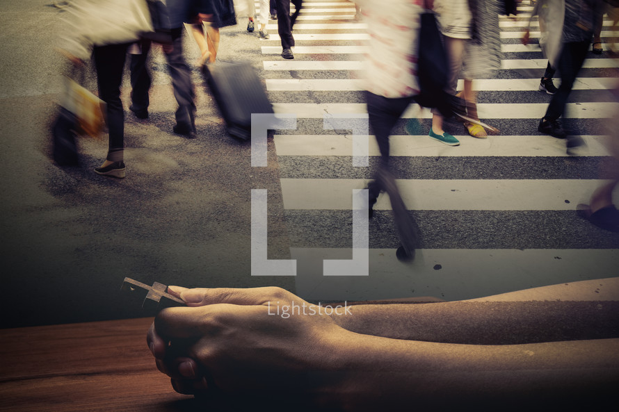 double exposure of people on a busy crosswalk and praying hands 